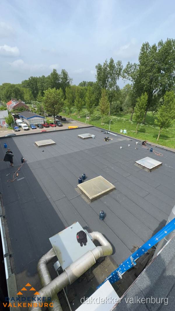 Dakdekker aan het werk op groot plat dak met bitumen in Valkenburg