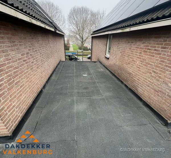 Plat dak met bitumen dakbedekking tussen bakstenen muren in Valkenburg Plat dak met bitumen dakbedekking tussen bakstenen muren in Valkenburg