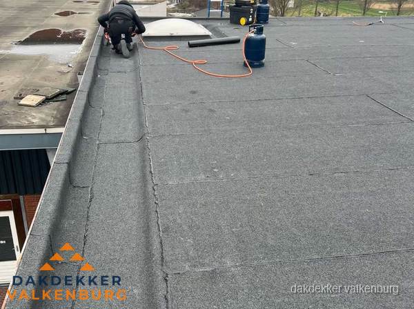 Dakdekker repareert bitumen dakbedekking op groot plat dak in Valkenburg