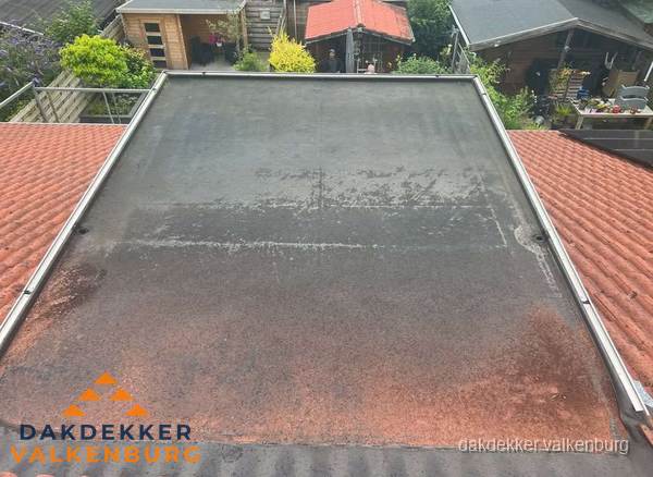 Verouderd plat dak met slijtage tussen schuine daken in Valkenburg Verouderd plat dak met slijtage tussen schuine daken in Valkenburg